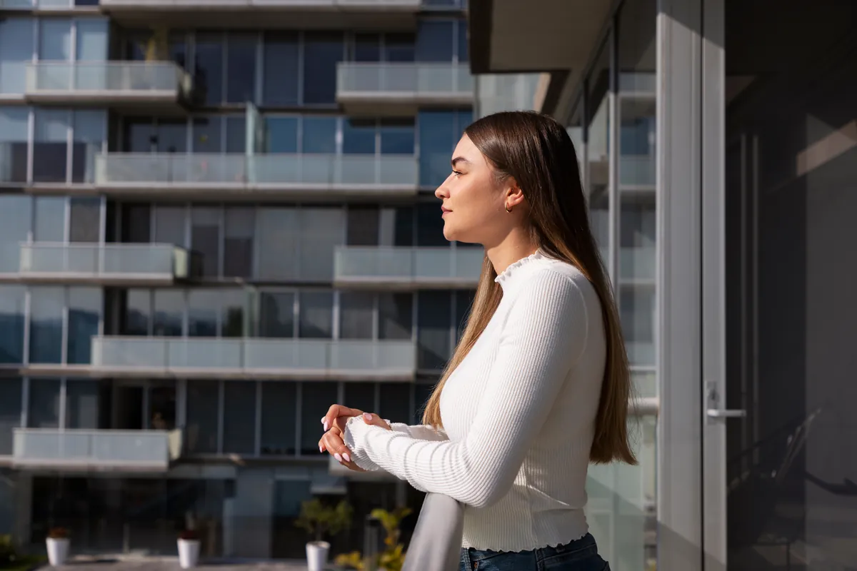 Mulher observando a cidade da varanda de um apartamento